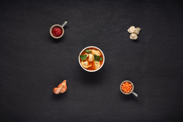 Obraz na płótnie Canvas chuchvara (dumplings) with ingredients tomato paste, carrot, onion on a black background top view