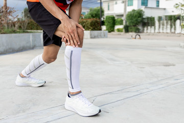 Close up on knee Injury. The man use hands hold on his knee while running in the park. space for text or design.