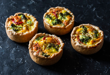 Broccoli, ham, cheddar pies on dark background, top view. Delicious appetizers, snack, tapas