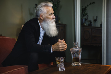 Handsome bearded senior man drinking whiskey