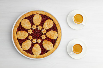 Homemade shortcrust cherry pie and two white cups of coffee espresso on white wooden table. Top view.