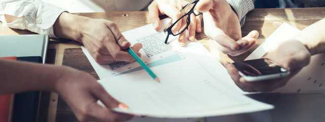 Business people working together. Loft office and smart casual dress code. Researching new product strategy. Electronic devices and paperwork on the table. Wide screen panoramic