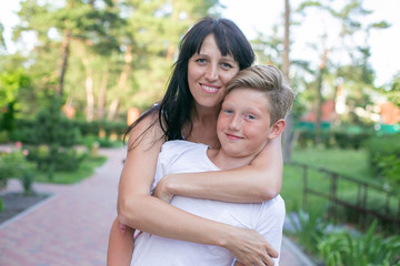 horizontal closeup portrait of a thirty year old woman with her teenage son in a summer park