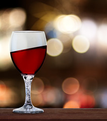 A glass of red wine in front of blured city lights. A tilt has been added for more dynamic.