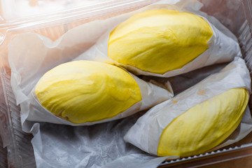 The close-up view of the fruit (durian) has an appetizing yellow color, arranged in a box for beauty, and available during the season.