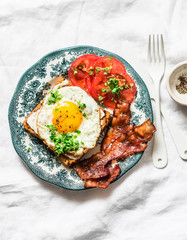 Nutritious breakfast - fried egg toast, bacon and tomatoes on a light background, top view