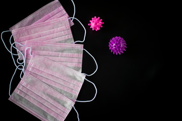 Coronavirus concept. Medical pink masks and viruses on a black background.