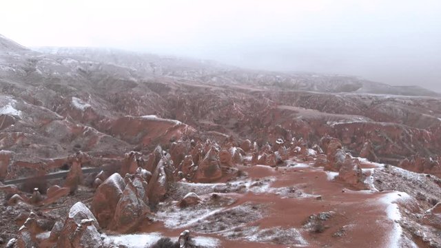 Fairy chimneys and cave houses surrounded by rock formations at Imaginary Valley in Cappadocia, Turkey. Tufa formations covered with snow in Devrent Valley in Cappadocia