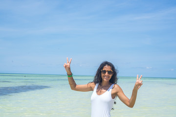 Fototapeta na wymiar Young indian woman doing victory gesture in the sea