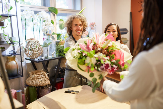 Floristen Team gibt Blumenstrauß an eine Kundin