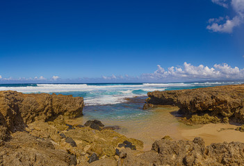 The clear blue waters of the Pacific Ocean splashing onto the rocky shoreline of