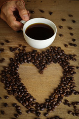 White coffee cup and coffee beans on wooden table with copyspace for text. Selective focus.