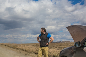 A man stands near a broken car.
