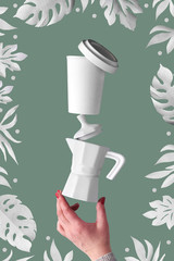Balancing zero waste coffee pyramid in female hands on salbei green background. Ceramic espresso coffee maker and eco friendly reusable bamboo coffee mug. Coffee beans and exotic paper leaves around.