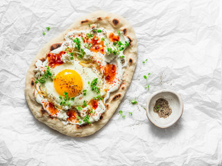 Delicious breakfast - flatbread with fried egg, greek yogurt, chili sauce and cheese on light...