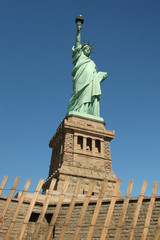 Obraz premium New York City (Manhattan)/ USA-5th September 2010: The panorama of the statue of liberty overlooks the dark blue sky and the skyscrapers of Manhattan to show the freedom of the United State.