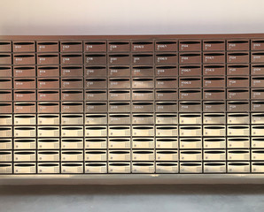 Front view of metallic postal cabinets with numbers and locks in many rows, all are locked.