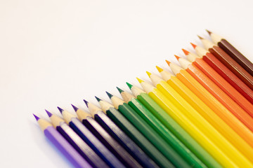 set of colored pencils on a background laid out by a rainbow