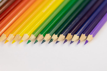 set of colored pencils on a background laid out by a rainbow