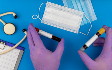 Flat lay composition with blood test tube and antiviral medical mask on blue background.
