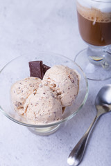 Homemade ice cream with chocolate chips in a bowl. Three balls of ice cream and a cup with coffee. Close-up.