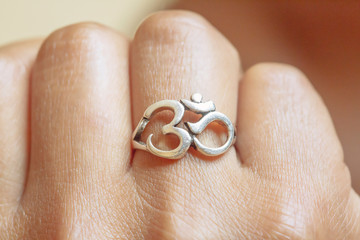 Hand wearing elegant silver ring in oriental shape of om
