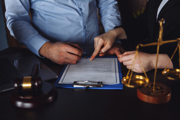 Hands of wife, husband signing decree of divorce, dissolution, canceling marriage, legal separation documents, filing divorce papers or premarital agreement prepared by lawyer. Wedding ring.