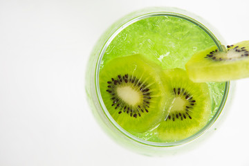 top view of green kiwi drink with ice in a glass decorated with sliced kiwi
