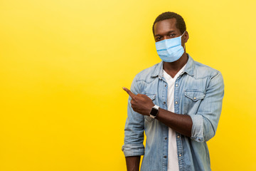 Look, advertise here! Portrait of positive man with surgical medical mask pointing left side and...