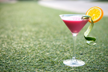 pink cocktail with lime and sliced orange