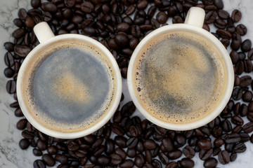 Top view of coffee cup with coffee beans on white marble background