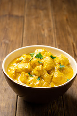 Chicken curry with parsley in bowl on wooden table