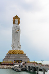 Fototapeta premium Statue of Guanyin on the territory of Buddhist center Nanshan on a cloudy day.