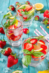 Strawberries and basil lemonade. Summer cold iced cocktail recipe, with fresh strawberry, lemon and basil leaves, wooden background copy space