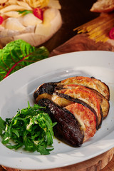 Eggplant Parmigiano. Baked eggplant with parmesan cheese and tomato  (a traditional Italian dish) on a wooden background. Close up.