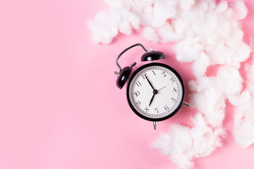 alarm clock on pink background with cloaks
