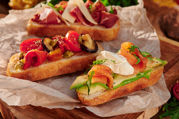 Italian bruschetta with roasted tomatoes, mozzarella cheese and herbs on a cutting board