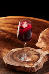 Red sangria in a glass on a wooden background. Traditional span alcoholic drink with red wine, fruits and ice on a wooden background. Close-up.
