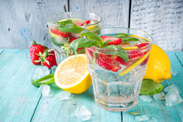 Strawberries and basil lemonade. Summer cold iced cocktail recipe, with fresh strawberry, lemon and basil leaves, wooden background copy space