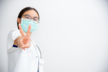 Studio portrait beautiful Asian young woman doctor raise two V shape finger wear a mask to safety Coronavirus to support in the fight against disease epidemic COVID 19 concept on blank gray background