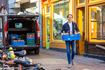 Delivery service by a local restaurant catering industry, young happy smiling entrepreneur walking to wards the camera with a blue chest filed with supplies
