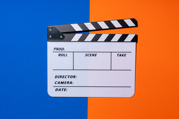 movie clapper on blue and orange color table background ; film, cinema and video photography concept