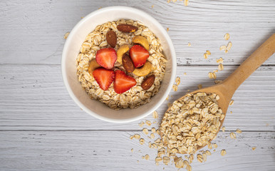 Bowls of oatmeal with nuts and fruits on white wood background. Top View. Healthy Homemade concept. vegan food