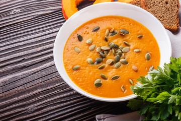 pumpkin carrot cream soup on rustic wooden background