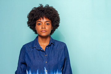 Fototapeta na wymiar Black young woman with black power hair wearing a blue jeans shirt on blue background