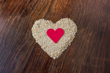 heart made of oats and red heart in the center on a wooden table