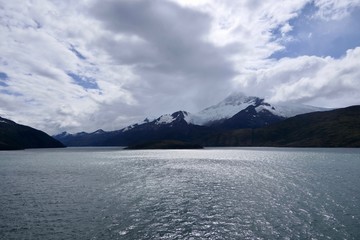 Snowy mountains in chilean fjord with clouds and shades on the water, Strait of Magellan