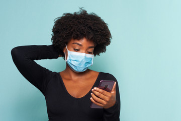 black muher with black power hair wearing protective mask with smartphone in hands