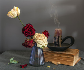 Still life with wilted roses, a book and an extinguished candle. Vintage. Interior.