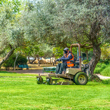 Man Wear Safety Masks As A Precaution During Outbreak The Coronavirus During Mows The Grass With Lawn Mower.